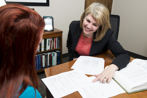 An image of Dianna Davis working with an employee while looking at paperwork on a desk.