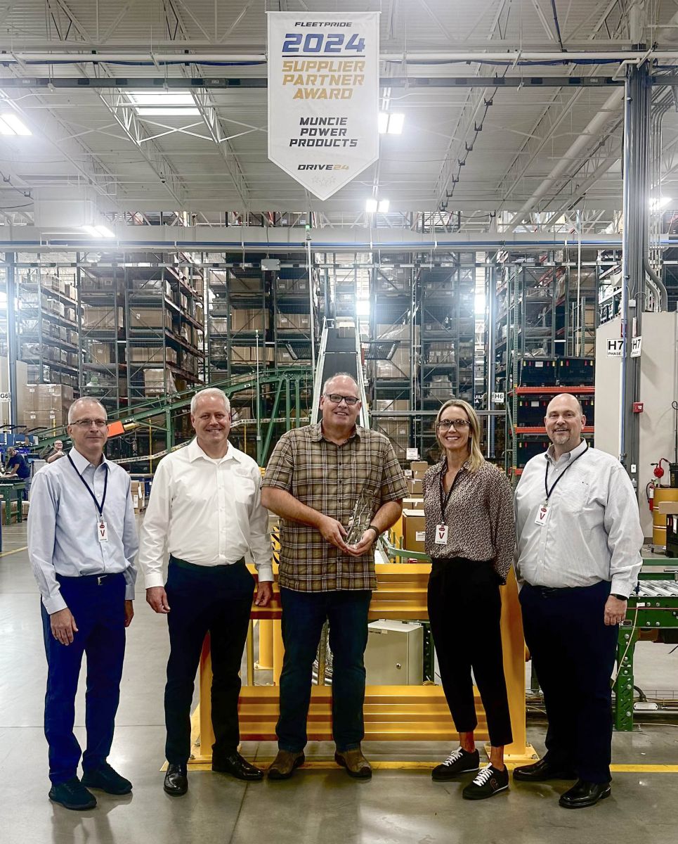 From left to right: Senior Category Manager John Buysse, Chief Commercial Officer Scott Huntsman, Director of USA Sales Mike Rasnick, Senior Director, Category Management Samantha Kaiser, and Vice President, Category Management Mike Keller pose for a photo under the Supplier of the Year banner provided by FleetPride.