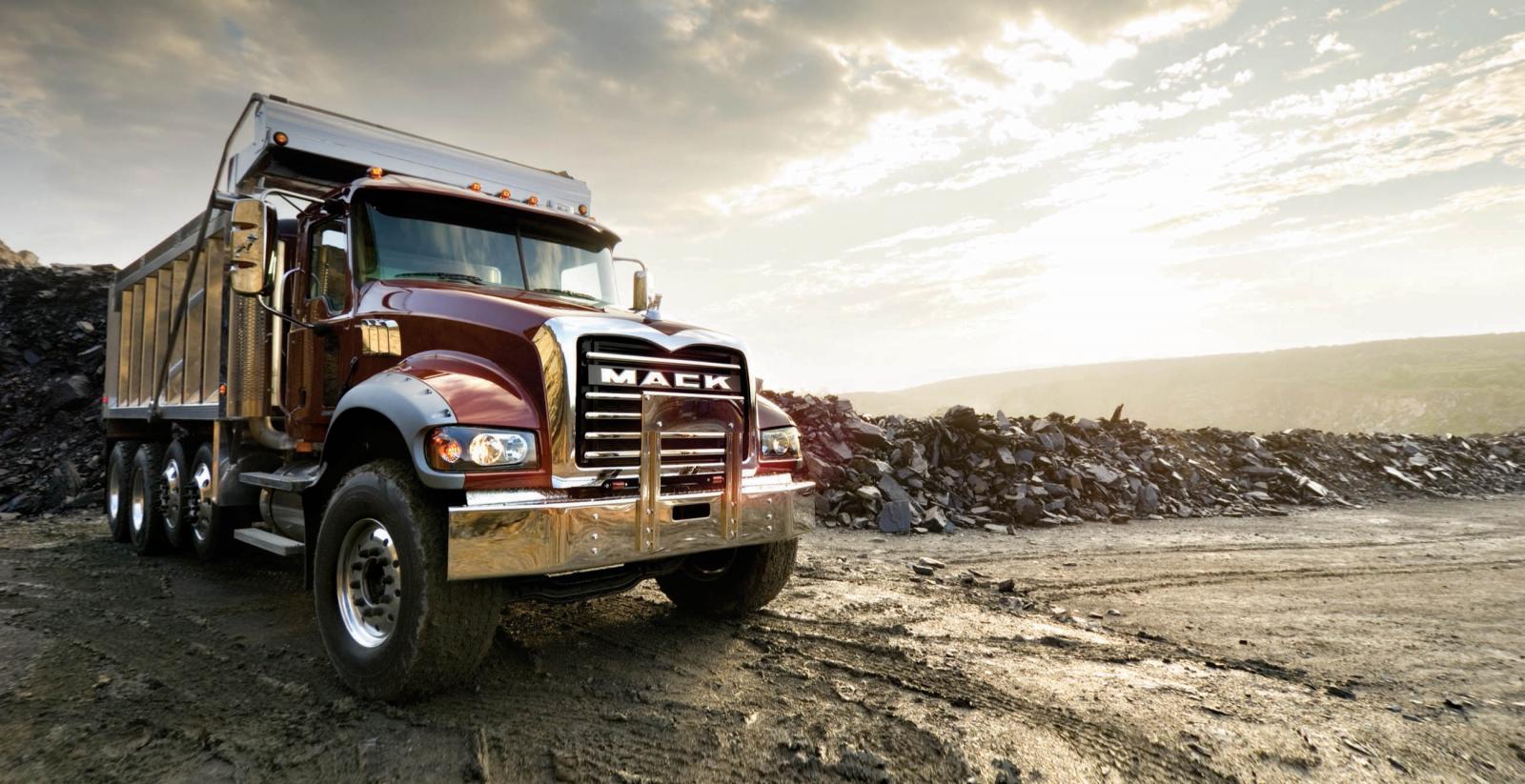 An image of a Mack dump truck with rubble in the background.