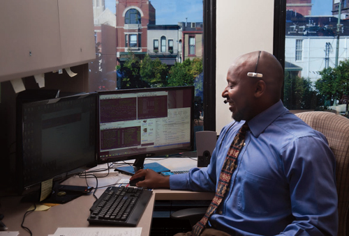 Jeffery Jackson sits at his desk while wearing a headset and working at the computer. 