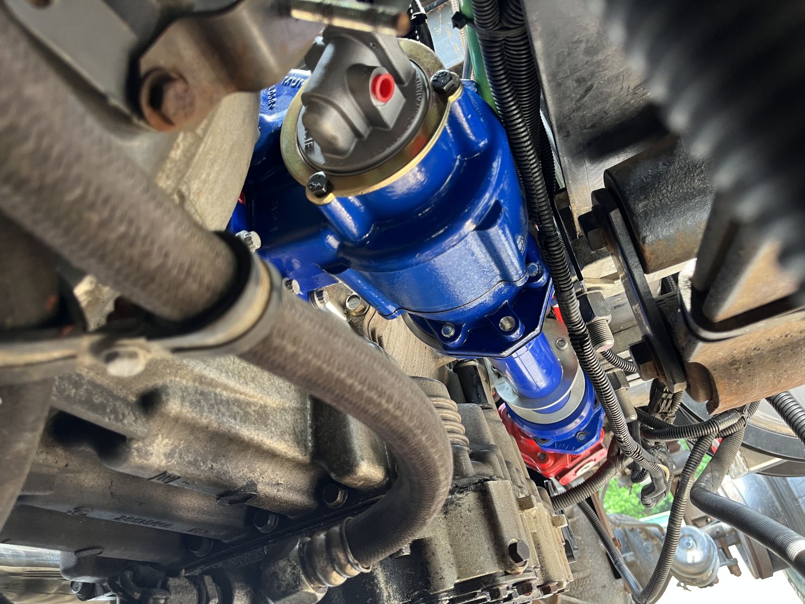 The image shows the A20 Series PTO mounted to a transmission with an EX Drive Shaft Extension leading to an Optimum W Series gear pump underneath a chassis.