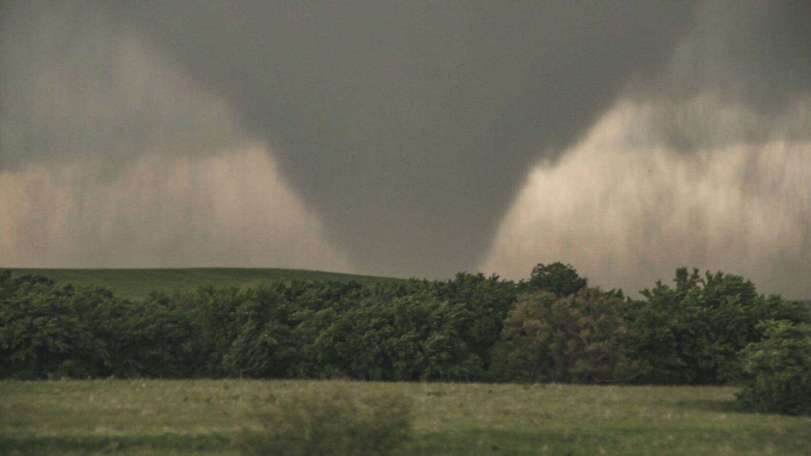 The image shows a large tornado in the distance.